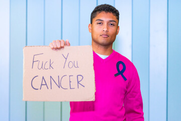 latino man holding anti-cancer protest sign with awareness ribbon