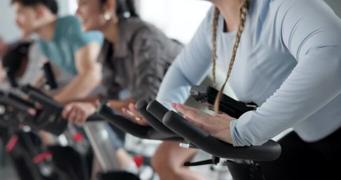 People, hands and fitness with bicycle for spin class, group exercise or workout at gym. Active, team or community cycling with coach or personal trainer together for cardio, health or wellness