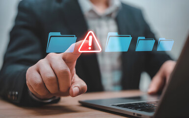 A businessman points at a digital warning alert near files indicating data breach risk cybersecurity threat and system failure requiring urgent attention for IT security.