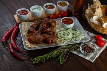Shashlik with sauces and fresh bread on wooden background