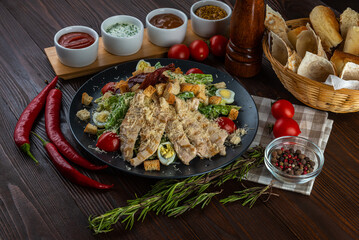 Caesar salad with chicken on wooden background