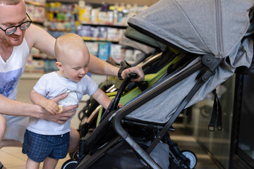 Happy baby choosing a new baby stroller in a shop.