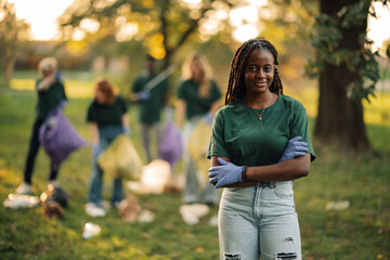 Young woman volunteer crossing arms with teammates picking up trash