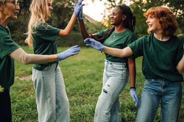 Happy volunteers giving high five after cleaning park