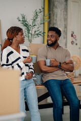 Happy couple drinking coffee during break from moving into new home