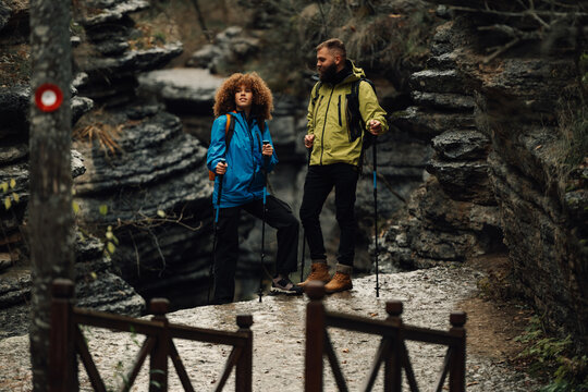 Hikers standing on rock formation enjoying scenic view in canyon - Powered by Adobe