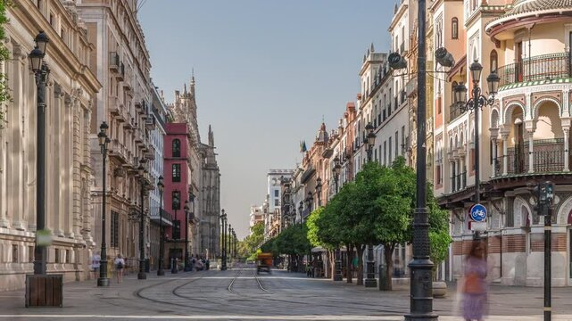 Pedestrians walking along Avda. de la Constitucion, major avenue in Casco Antiguo district of Seville, Spain. Timelapse near Edificio de la Adriatica, historical buildings and passing trams