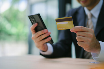 Online shopping. Man hand holding credit card and using laptop at office, Businessman or entrepreneur working , e-commerce, internet banking, spending money, working from home concept