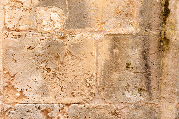 Close-up of an aged, weathered stone wall with warm beige and tan tones