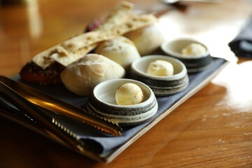 Tasty buns, crackers and butter served on wooden table, closeup