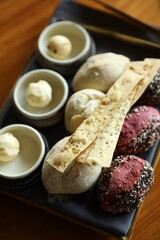 Tasty buns, crackers and butter served on wooden table, closeup