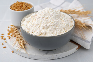 Wheat flour, grain and spikes on white table, closeup
