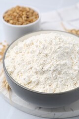 Wheat flour, grain and spikes on white table, closeup