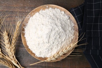 Wheat flour and spikes on wooden table, flat lay