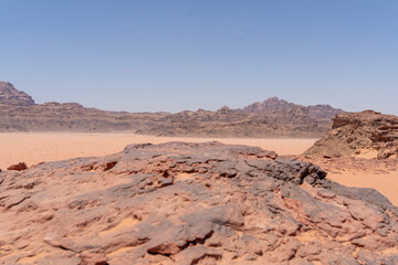 Desert Landscape: A sun-drenched landscape reveals the raw beauty of the desert with rolling red hills under a clear blue sky, a testament to nature's rugged artistry.