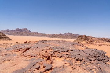Desert Landscape under Clear Sky: A vast, sweeping desert scene unfolds under a flawless, azure sky, with rugged.