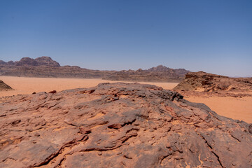 Naklejka premium Desert Landscape: A captivating panoramic view of a vast desert under a clear, azure sky, showcasing rugged terrain and a sense of expansive space.