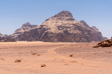 Desert Landscape: A stunning panoramic view of a desert landscape, featuring vast, rolling dunes, a rugged mountain range, and a clear, azure sky, bathed in the warm, golden light of the sun.