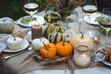 Fall still-life. Orange pumpkins, dry flowers and candles on linen tablecloth. Dinner table outdoors in the garden. Cozy autumn concept., simple handmade decoration, countryside style