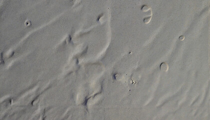 Sand texture with patterns and footprints on a sunny beach  