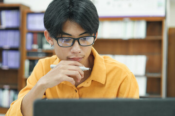 Young collage student using computer and mobile device studying online.