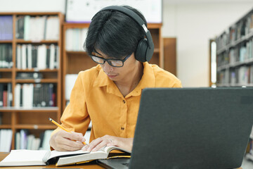 Young collage student using computer and mobile device studying online.