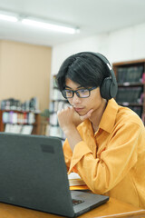 Young collage student using computer and mobile device studying online.