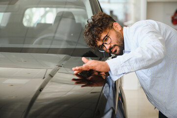 Customer carefully inspecting new car at dealership