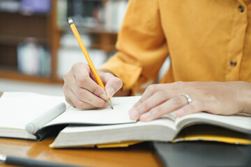 Closeup man hands using writing in a book in university library.