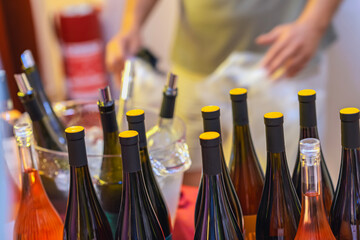Assorted wine bottles with yellow caps arranged on ice bucket stand at public event. Concept of cold wine tasting, organized bar, social gathering, party