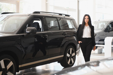 Saleswoman presenting a new black suv in a car dealership