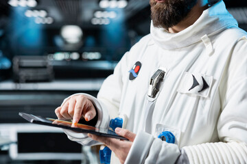 Close up of astronaut running telemetry software on tablet to confirm suit integrity. Orbital...