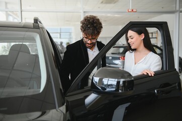 Arab Car salesman showing new vehicle to woman at dealership
