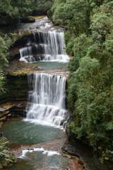 Wei sawdong waterfall  of Meghalaya cascades down mossy rocks amidst lush green forest.