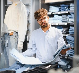 Salesman holding jeans in clothing store