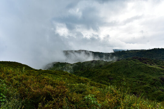 White clouds billow over rolling green hills, expansive sky in Meghalaya. 