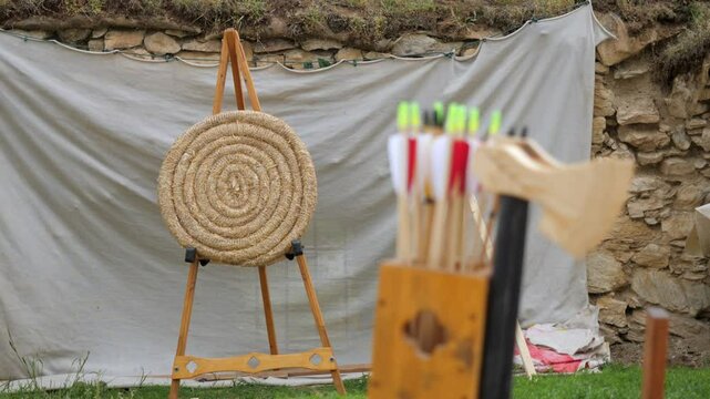 focusing on medieval straw target on a stand with arrows with red tips in the foreground