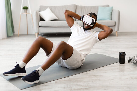 Virtual Workout. African Man Wearing VR Glasses Doing Abs Exercise At Home. Training Via Augmented Reality Application, Futuristic Fitness, Smart Sport And Technology Concept