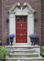 Elegant maroon colored front door with decorative scroll work frame