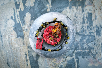 Gourmet beef tartar made of raw beef fillet with capers and balsamic vinegar smoke sauce served as...