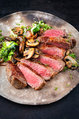 Traditional barbecue grass-fed dry aged roast beef steak  with mushrooms and greens served as...