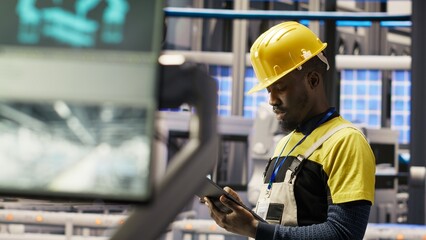 Engineer oversees solar panel production lines equipment using tablet app. Worker maintains photovoltaic assembly systems in automated industry 4.0 factory using digital device application, camera B