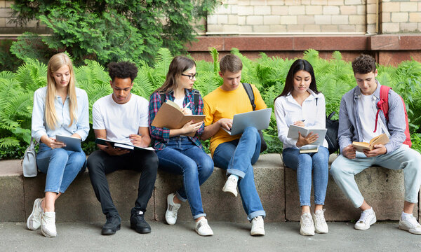 Students preparing for lecture. Teens sitting in university campus with books and devices