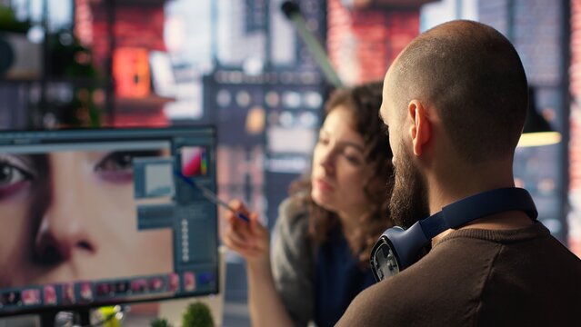 Graphic designer and photographer collaborate in a modern studio, using photo editing software and tools on PC. Team does retouching with advanced image adjustment tools. Camera B. - Powered by Adobe