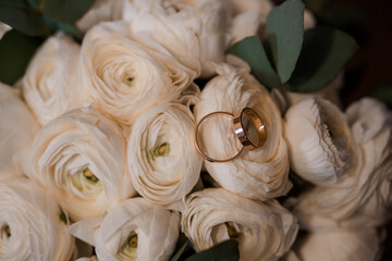 Wedding Rings on White Ranunculus Bouquet: Romantic Ceremony Symbolism with Golden Bands and Soft...