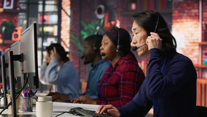 Experienced call center employee listening to customer inquiries and complaints. Asian senior customer service representative assisting customers with issues related to products or services, camera A