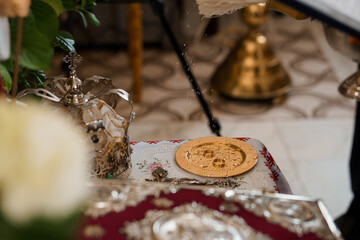 Eastern Orthodox Wedding Ceremony: Blessing of the Rings with Silverware and Floral Arrangement, Gold Disks, Red Textile Background