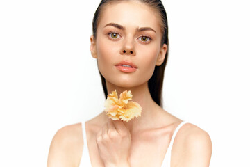 Beautiful model with vibrant flower, showcasing natural beauty and elegance against a clean white background with soft lighting.