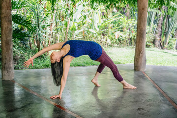 Woman practicing wild thing yoga pose in tropical retreat