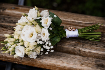 Rustic Wedding Rings and White Bridal Bouquet on Wooden Bench. Love, Romance, Commitment, Ceremony,...